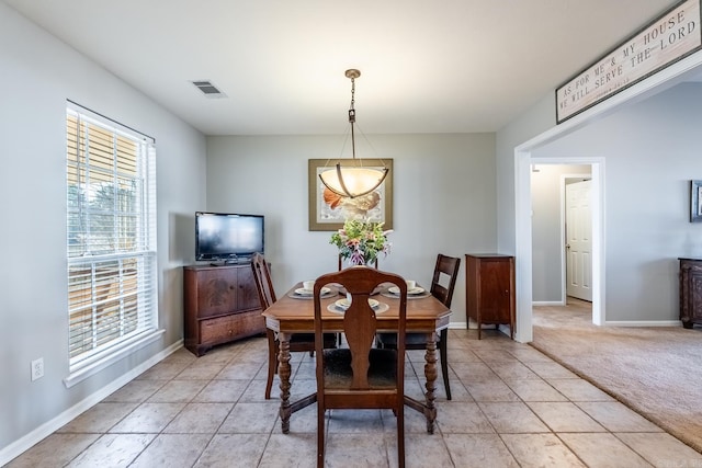 dining area featuring light carpet, light tile patterned floors, visible vents, and baseboards