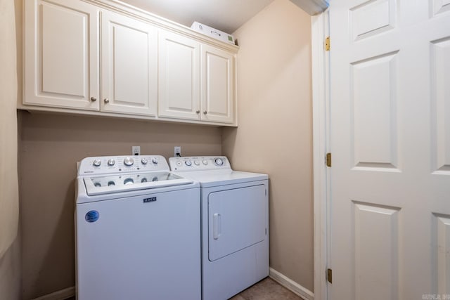 washroom with cabinet space, baseboards, and separate washer and dryer