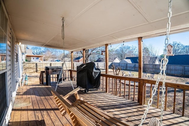 wooden deck with a fenced backyard and a grill