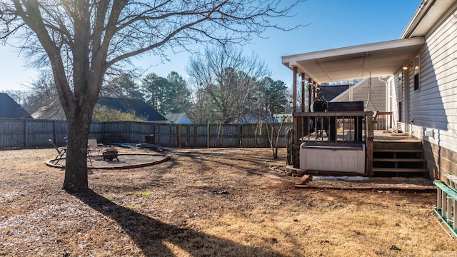 view of yard with a hot tub, a fenced backyard, a fire pit, and a wooden deck