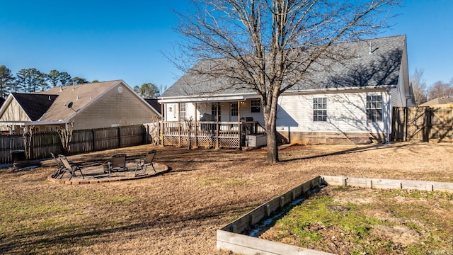 rear view of property featuring an outdoor fire pit, a lawn, a fenced backyard, roof with shingles, and a wooden deck