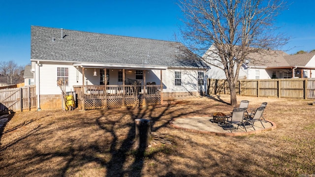 back of property featuring an outdoor fire pit, a fenced backyard, roof with shingles, a deck, and a yard