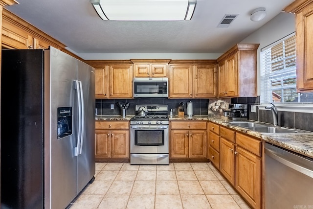 kitchen featuring light tile patterned floors, tasteful backsplash, visible vents, appliances with stainless steel finishes, and a sink