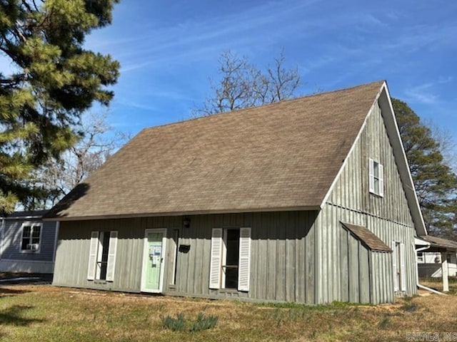 back of property with a shingled roof and a yard