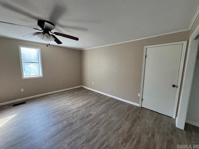 spare room with baseboards, visible vents, dark wood-style floors, ceiling fan, and crown molding