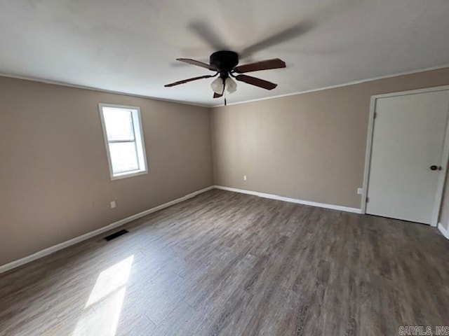 spare room featuring ornamental molding, dark wood finished floors, visible vents, and baseboards