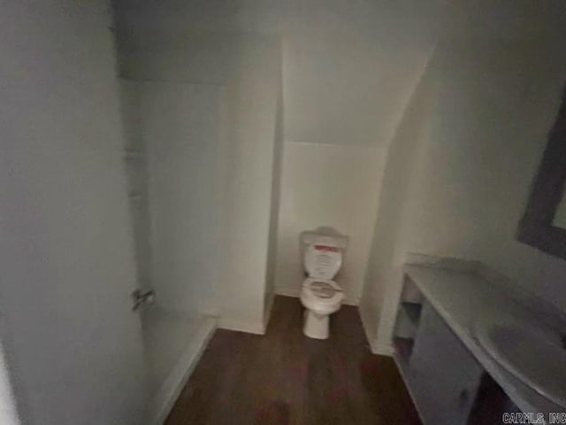 bathroom with toilet, vaulted ceiling, and wood finished floors