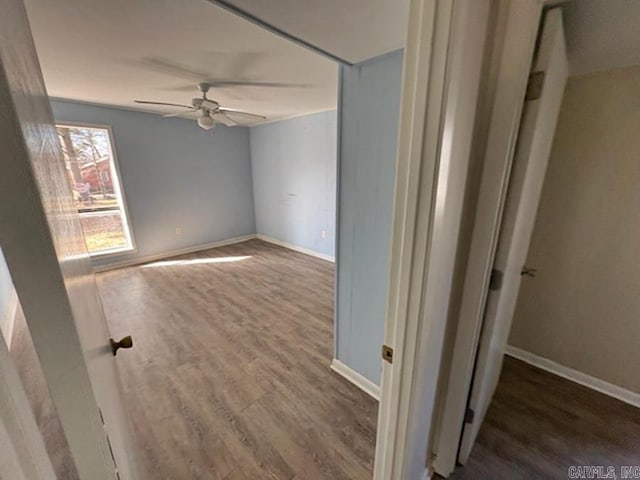 unfurnished room featuring ceiling fan, dark wood-type flooring, and baseboards