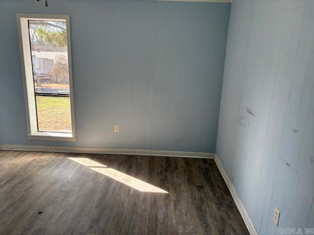 empty room featuring baseboards and dark wood-type flooring