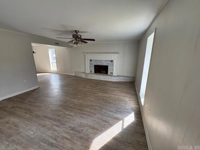 unfurnished living room with a fireplace, a ceiling fan, baseboards, dark wood finished floors, and crown molding