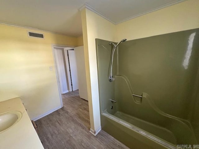 bathroom featuring baseboards, visible vents, ornamental molding, wood finished floors, and shower / bathtub combination