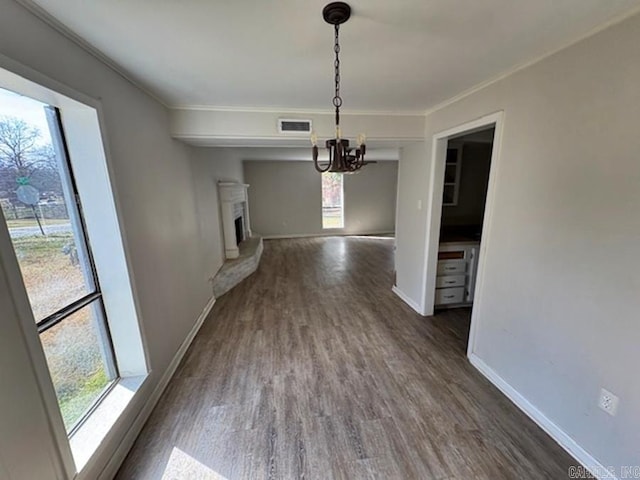 unfurnished dining area featuring dark wood-style floors, baseboards, ornamental molding, and a fireplace with raised hearth