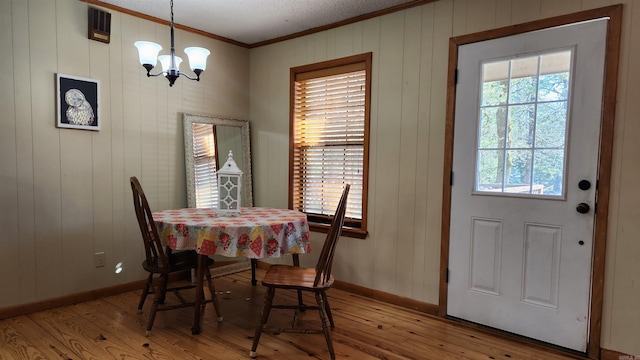 dining space with a chandelier, light wood-type flooring, a wealth of natural light, and crown molding