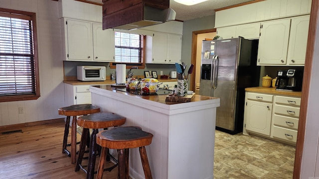 kitchen featuring a breakfast bar, white cabinetry, and stainless steel refrigerator with ice dispenser