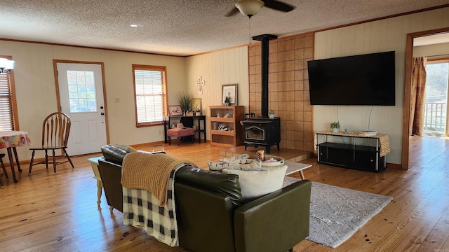 living area featuring a wood stove, crown molding, and light wood finished floors