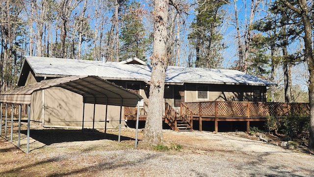 exterior space with metal roof, a carport, a deck, and driveway