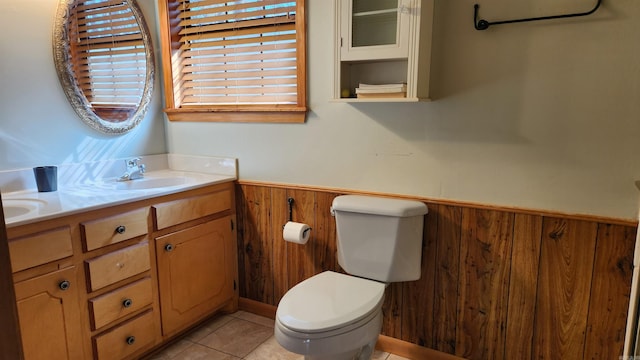 bathroom featuring double vanity, wooden walls, wainscoting, tile patterned flooring, and a sink