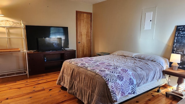 bedroom featuring electric panel and wood finished floors