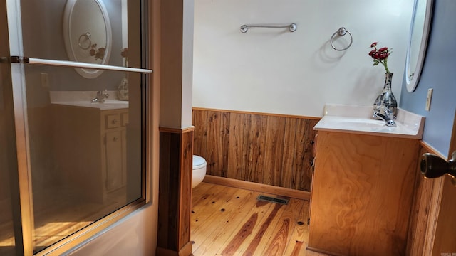 full bathroom with toilet, wooden walls, a wainscoted wall, visible vents, and vanity