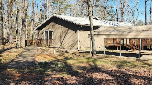 view of side of home featuring stairs, a carport, metal roof, and a wooden deck