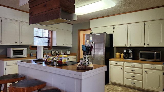 kitchen with a toaster, white cabinets, stainless steel appliances, a textured ceiling, and premium range hood