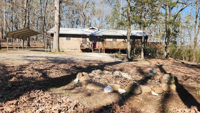 rear view of property featuring a carport, metal roof, driveway, and a wooden deck