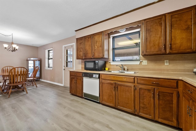 kitchen featuring brown cabinets, light countertops, hanging light fixtures, black microwave, and dishwasher