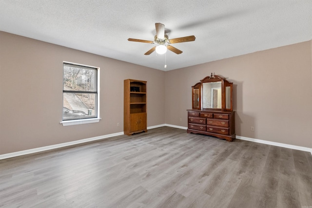 unfurnished bedroom featuring a textured ceiling, ceiling fan, light wood-style flooring, and baseboards