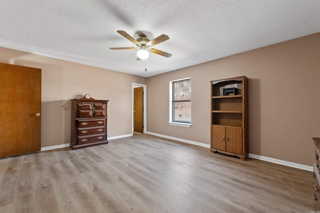 unfurnished bedroom with a textured ceiling, light wood-type flooring, a ceiling fan, and baseboards