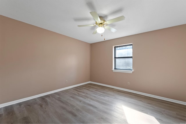 empty room featuring a ceiling fan, baseboards, and wood finished floors