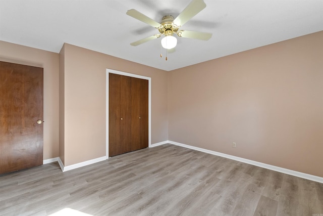 unfurnished bedroom featuring light wood-style floors, a closet, baseboards, and a ceiling fan