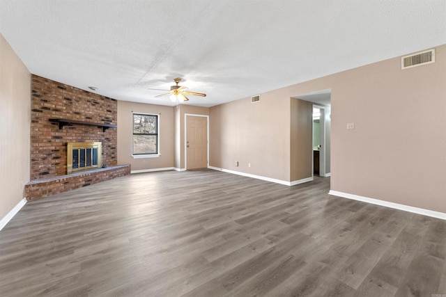 unfurnished living room with a fireplace, visible vents, and dark wood finished floors