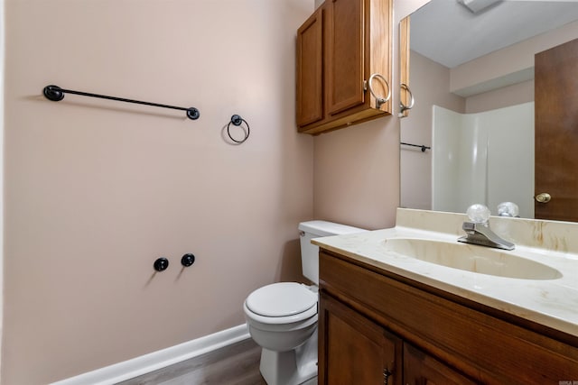 bathroom featuring toilet, baseboards, wood finished floors, and vanity