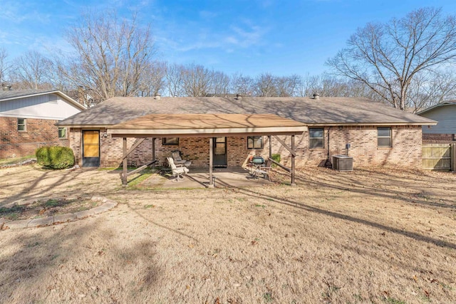 back of property with a yard, central AC, brick siding, and a patio