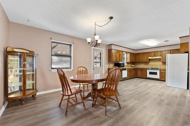 dining area with baseboards, a textured ceiling, light wood-style flooring, and a notable chandelier