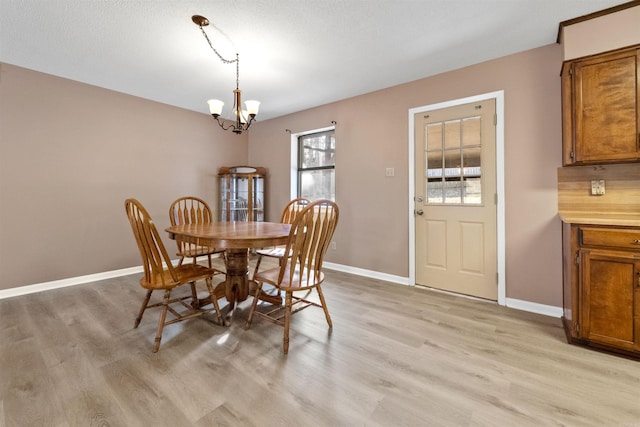 dining space featuring baseboards, light wood finished floors, and an inviting chandelier