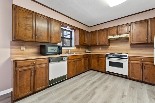 kitchen featuring brown cabinets, light countertops, light wood-style flooring, white appliances, and under cabinet range hood