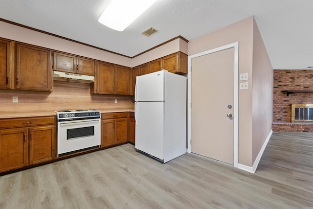 kitchen with brown cabinets, light countertops, visible vents, white appliances, and under cabinet range hood