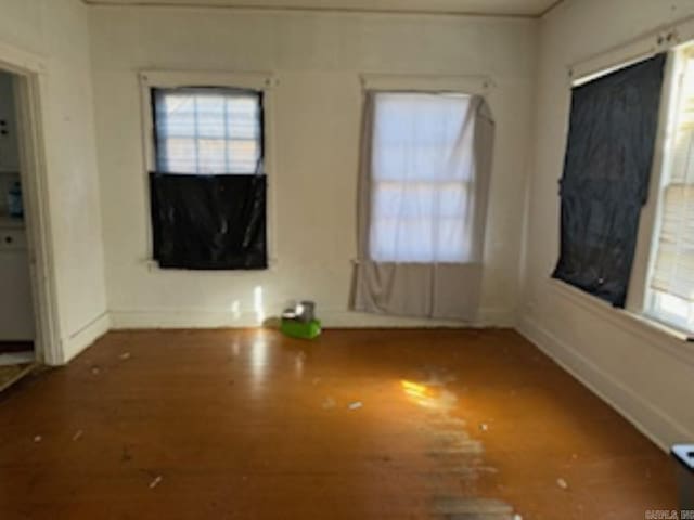 empty room featuring dark wood-style floors, a wealth of natural light, and baseboards