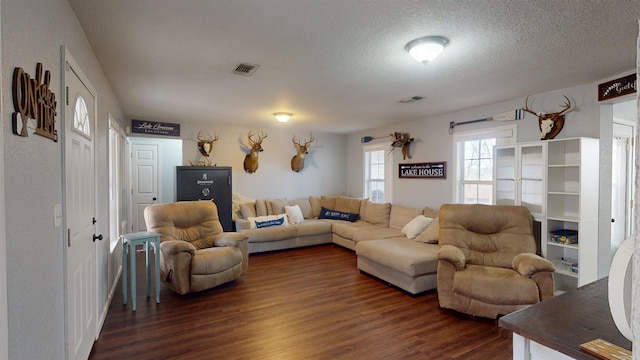 living area with dark wood-style floors, a textured ceiling, and visible vents