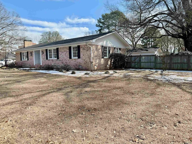 view of front of house with brick siding, fence, crawl space, a front lawn, and a chimney