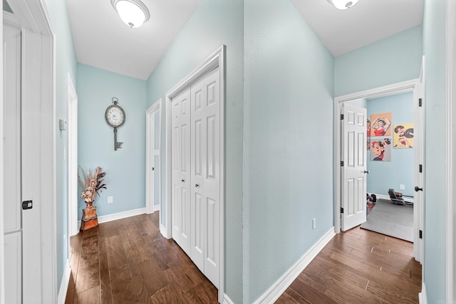 hall featuring dark wood-type flooring and baseboards