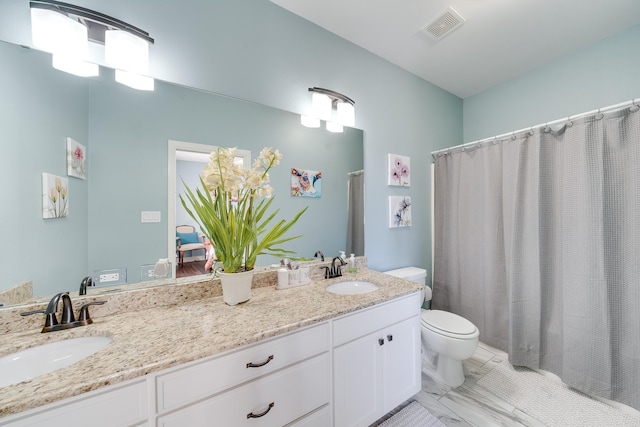 bathroom with double vanity, visible vents, toilet, and a sink