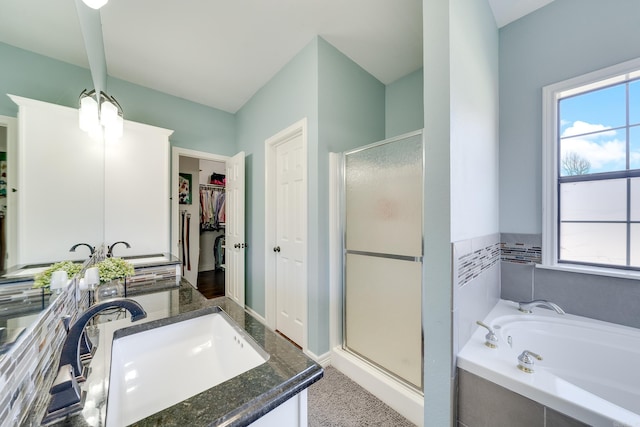 full bath featuring a stall shower, a walk in closet, vanity, and a bath