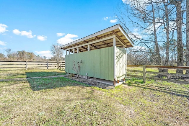 view of outbuilding featuring fence, an outdoor structure, and a rural view