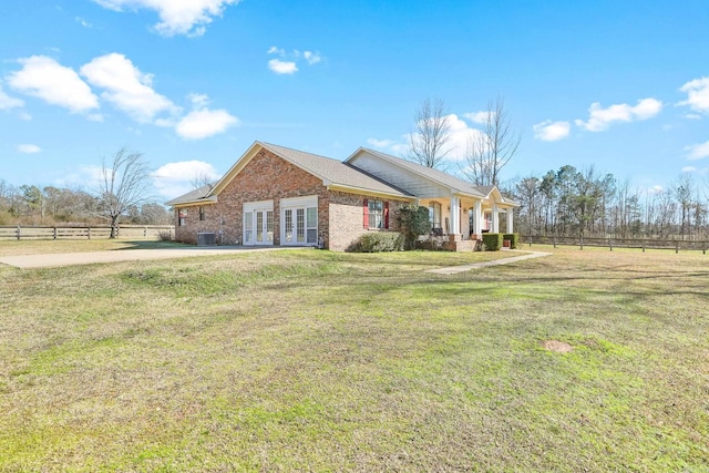 view of front facade with french doors, brick siding, fence, and a front lawn