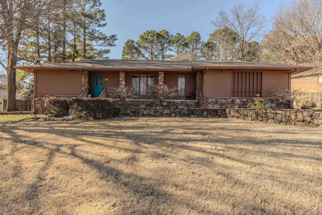 rear view of house with stone siding and a lawn