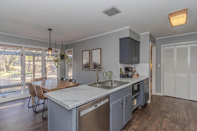 kitchen featuring dark wood finished floors, a peninsula, light countertops, a sink, and stainless steel appliances