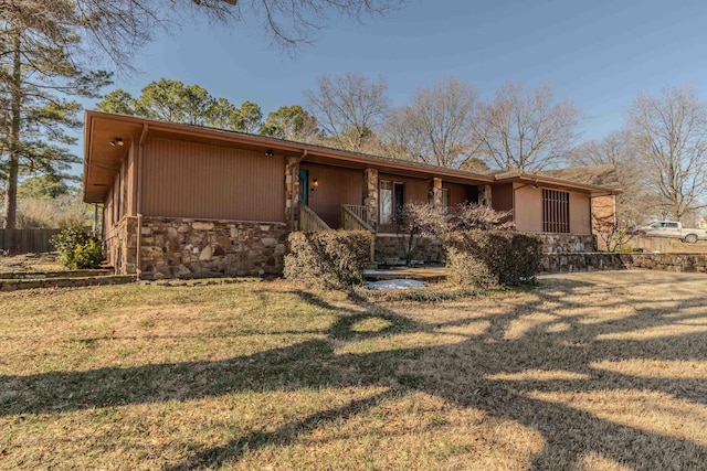 view of front of home with stone siding, a front yard, and fence