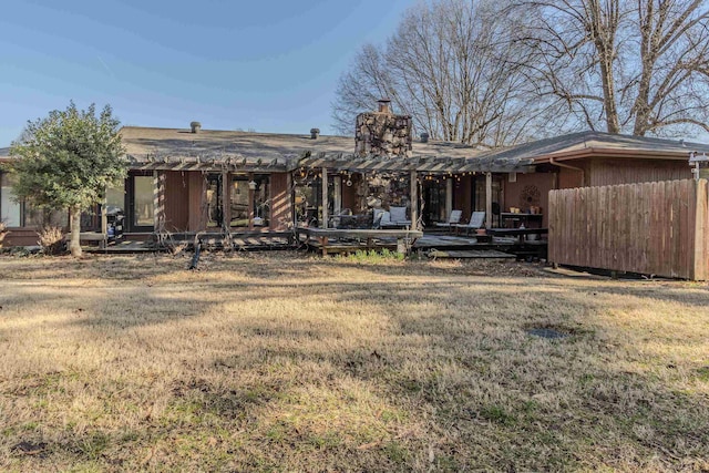 back of house featuring a pergola, a lawn, and a chimney